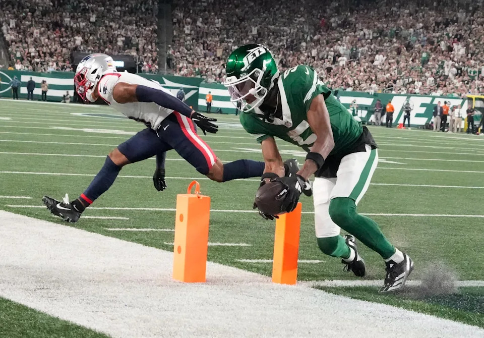 New York Jets wide receiver Garrett Wilson (5) scores a 3rd quarter touchdown in front of New England Patriots cornerback Christian Gonzalez.