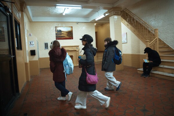 Gulhayo Yuldosheva's kids leave for school in an apartment building where tenants report maintenance issues and pest infestations, in the Bronx borough of New York, Tuesday, March 17, 2026. (AP Photo/Andres Kudacki)