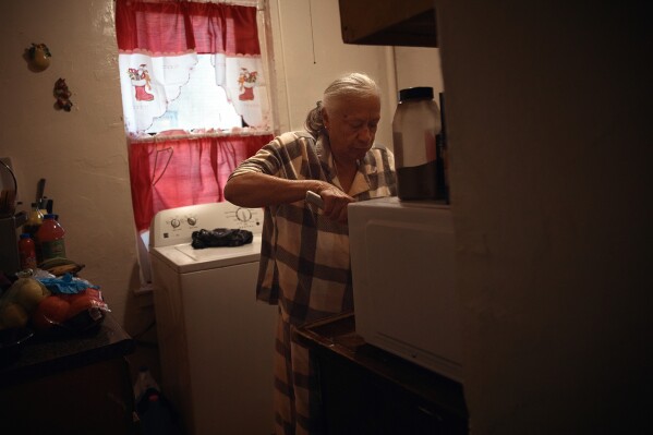 Maria Rodriguez prepares food in an apartment building where tenants report maintenance issues and pest infestations, in the Bronx borough of New York, Tuesday, March 17, 2026. (AP Photo/Andres Kudacki)
