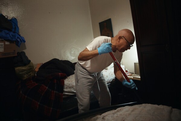 Francisco Medina cleans one of his home's bedroom floors in an apartment building where tenants report maintenance issues and pest infestations, in the Bronx borough of New York, Tuesday, March 17, 2026. (AP Photo/Andres Kudacki)