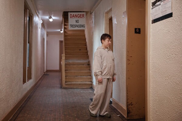 Gulhayo Yuldosheva's son, Heriberto, 11, stands in an apartment building where tenants report maintenance issues and pest infestations, in the Bronx borough of New York, Tuesday, March 17, 2026. (AP Photo/Andres Kudacki)