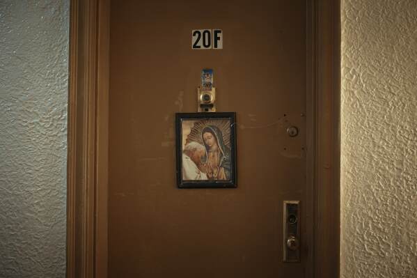 A religious image hangs from a front door in an apartment building where tenants report maintenance issues and pest infestations, in the Bronx borough of New York, Tuesday, March 17, 2026. (AP Photo/Andres Kudacki)