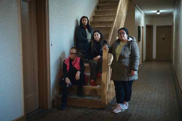Gulhayo Yuldosheva, 33 , center right, Marina Quiroz, 65, top, pose for a portrait with other two residents in an apartment building where tenants report maintenance issues and pest infestations, in the Bronx borough of New York, Tuesday, March 17, 2026. (AP Photo/Andres Kudacki)