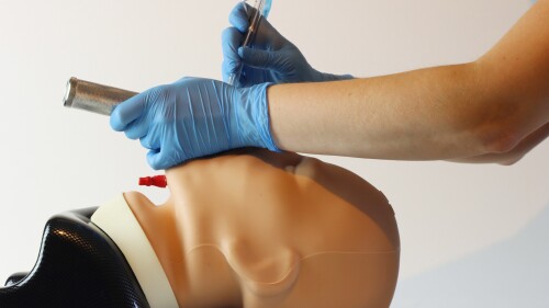 Intubating a simulated patient with a laryngoscope and a endotracheal tube. Health care professional wearing surgical gloves and scrubs.