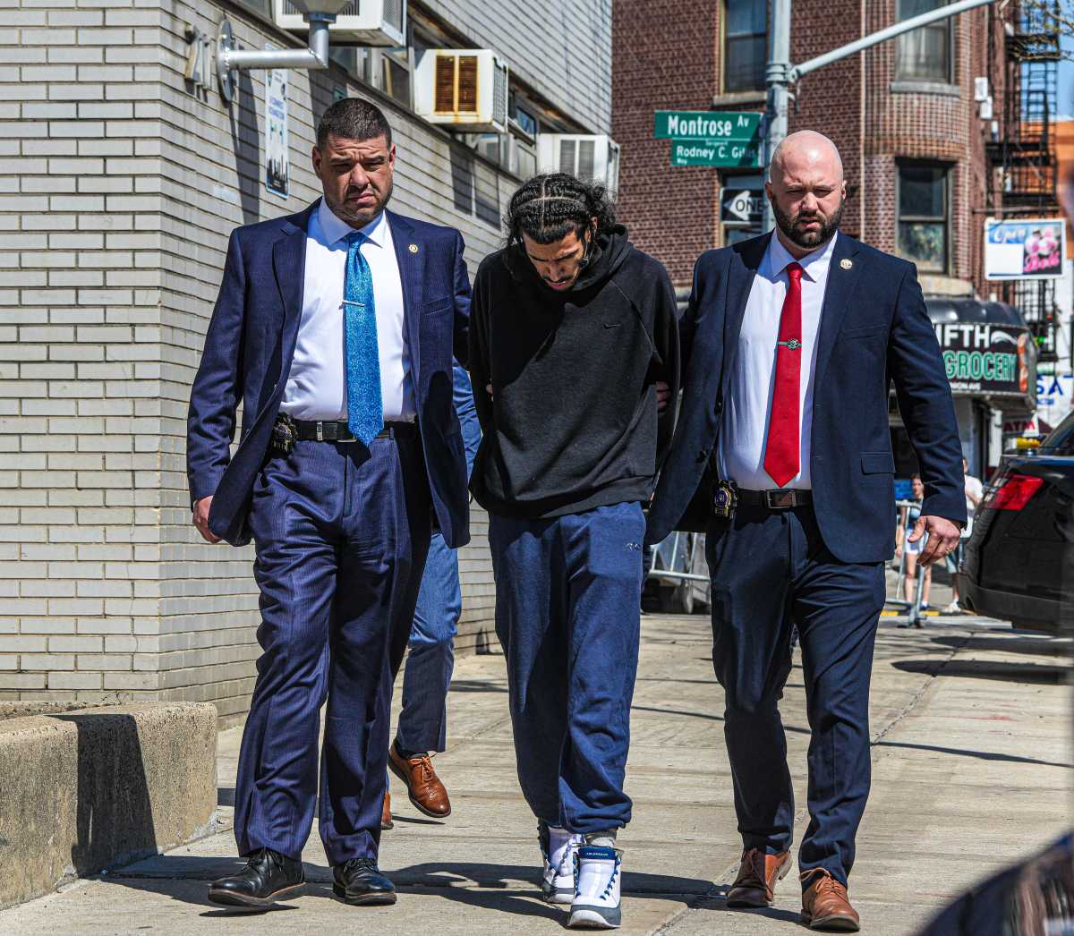 suspect in Brooklyn baby shooting walks with head down accompanied by nypd detectives following arrest