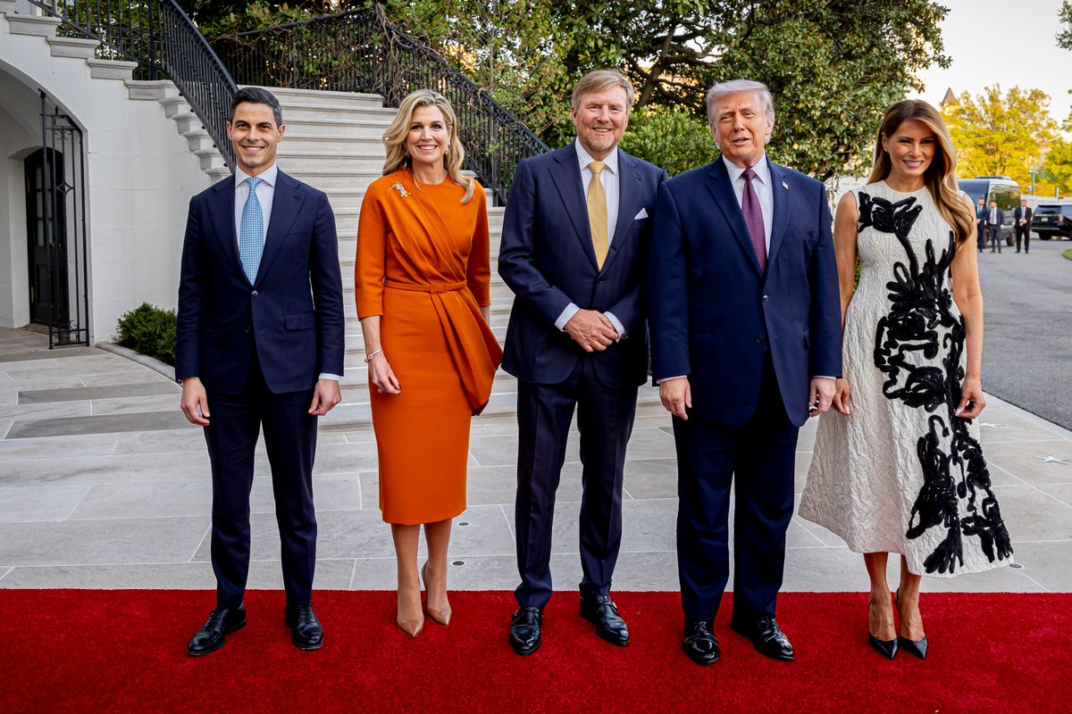 Standing beside Queen Máxima, who embraced a vibrant burnt-orange dress with a cinched waist and draped detailing, Melania’s look offered a study in contrast. 