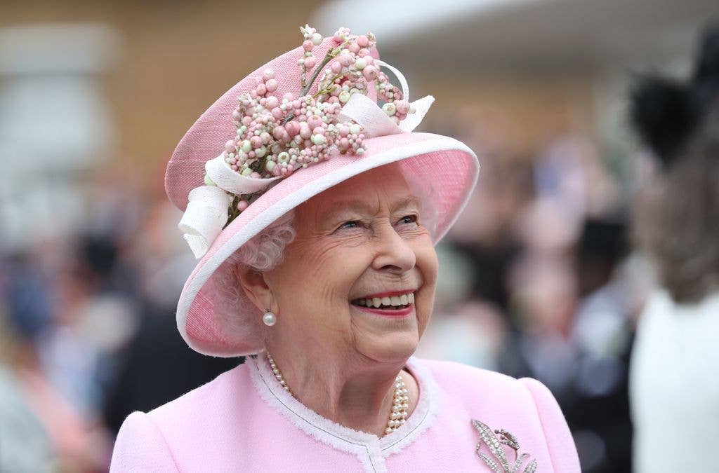 Queen Elizabeth smiling in soft pink hat and coat dress