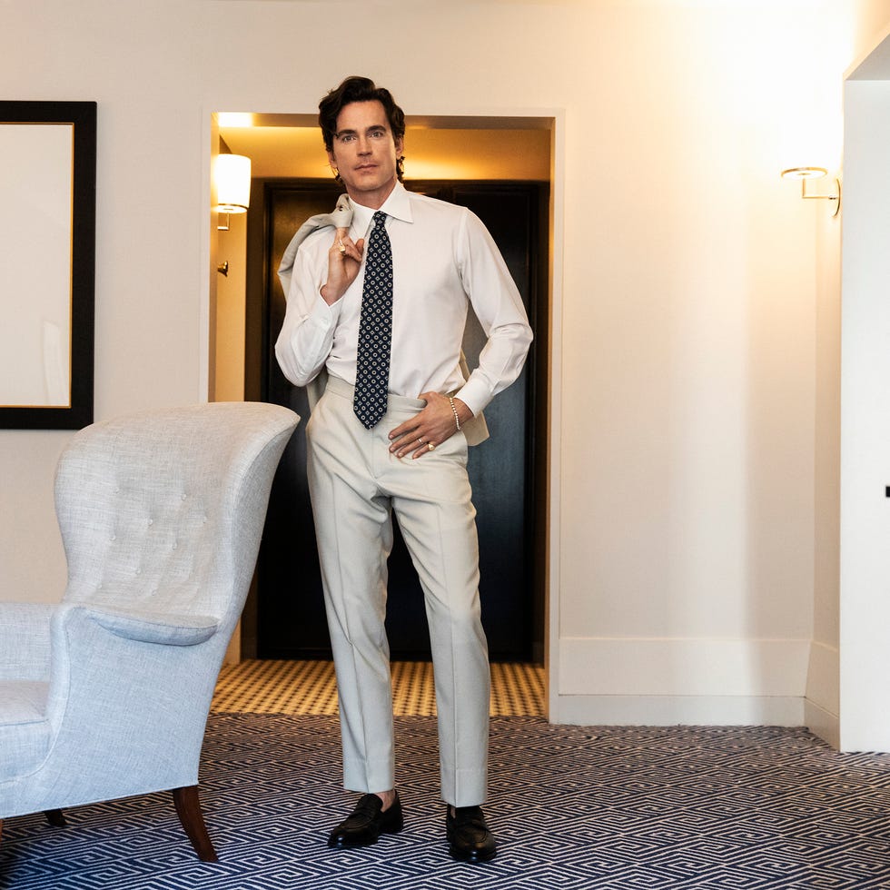 A well-dressed individual stands confidently in a stylish room.