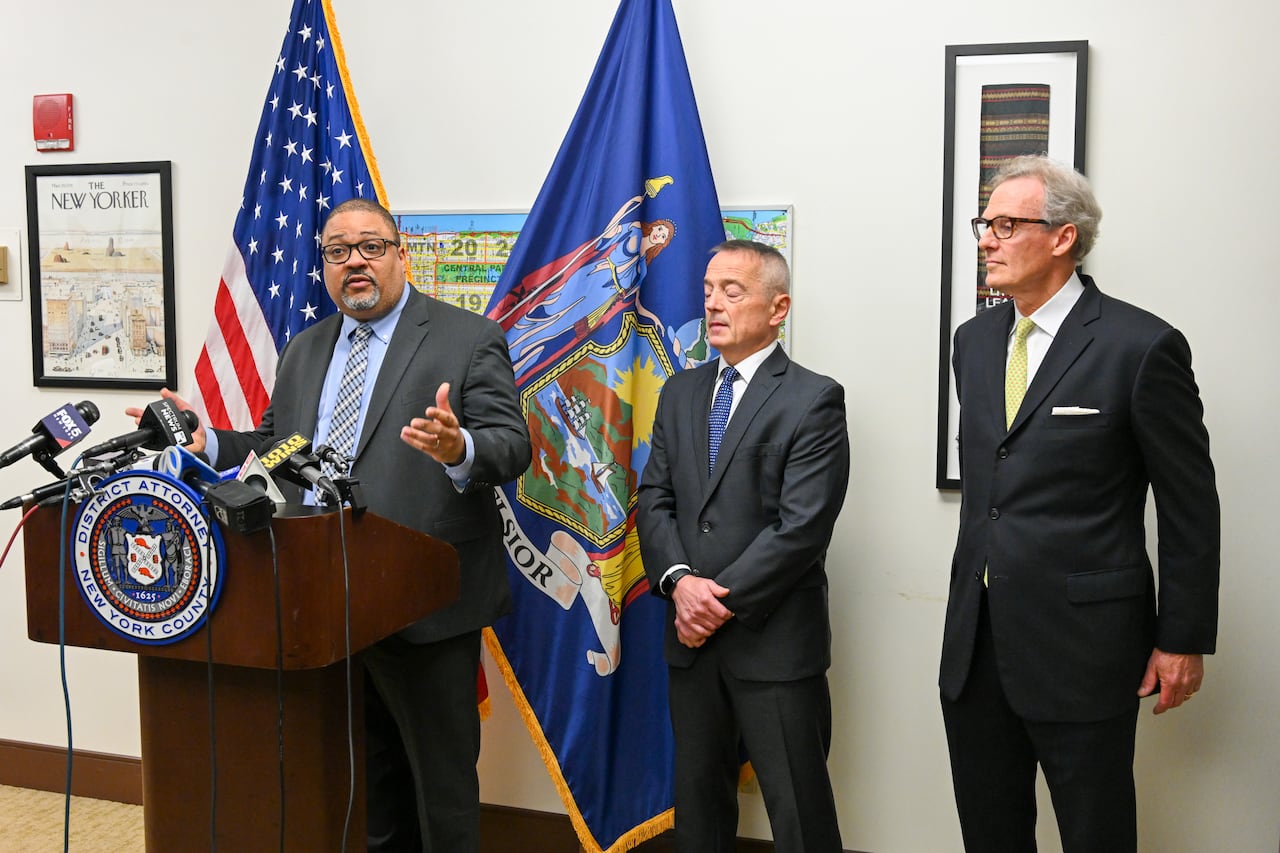 Three men in suits stand at a podium