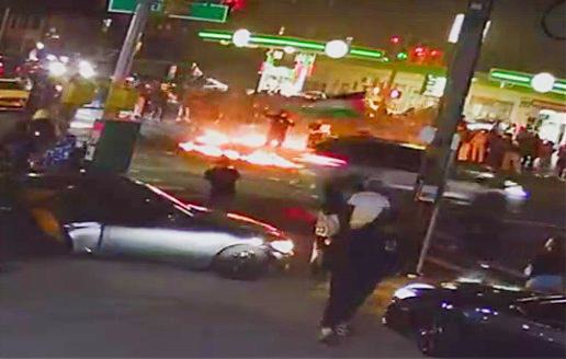 During the chaotic Queens car takeover, the revelers repeatedly lit a fire in the intersection, which is bounded by gas stations. A car flying a large Palestinian flag was one of the vehicles that circled the flames. (Screengrab from video obtained by New York Daily News)