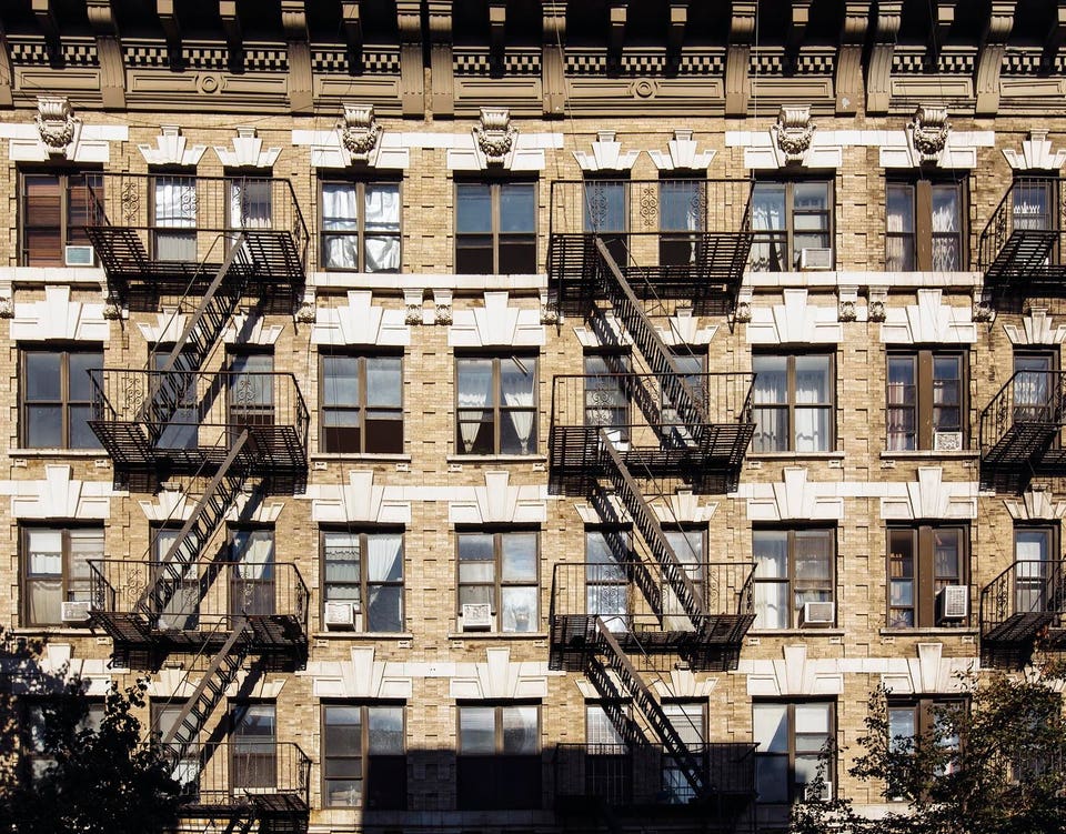 Facade of an old residential building with fire escape ladders in Brooklyn, New York City, USA