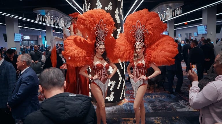 Showgirls in feathered costumes pose for photos during the opening...