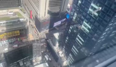 Window washer dangles outside building high above Times Square in NYC