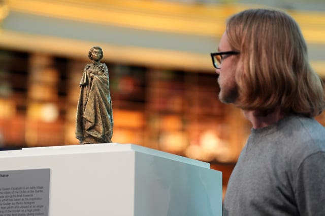 A man looking at a maquette of the Queen on a plinth at the British Museum