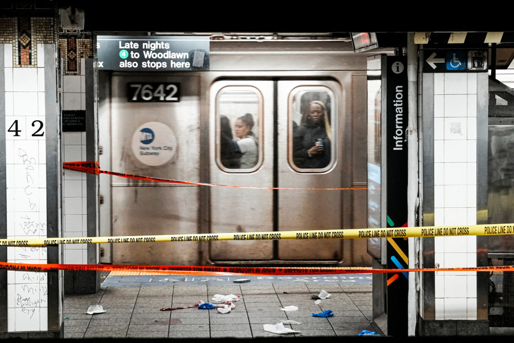 Commuters in a train pass near the crime scene where three people were attacked inside the subway system at Grand Central ...
