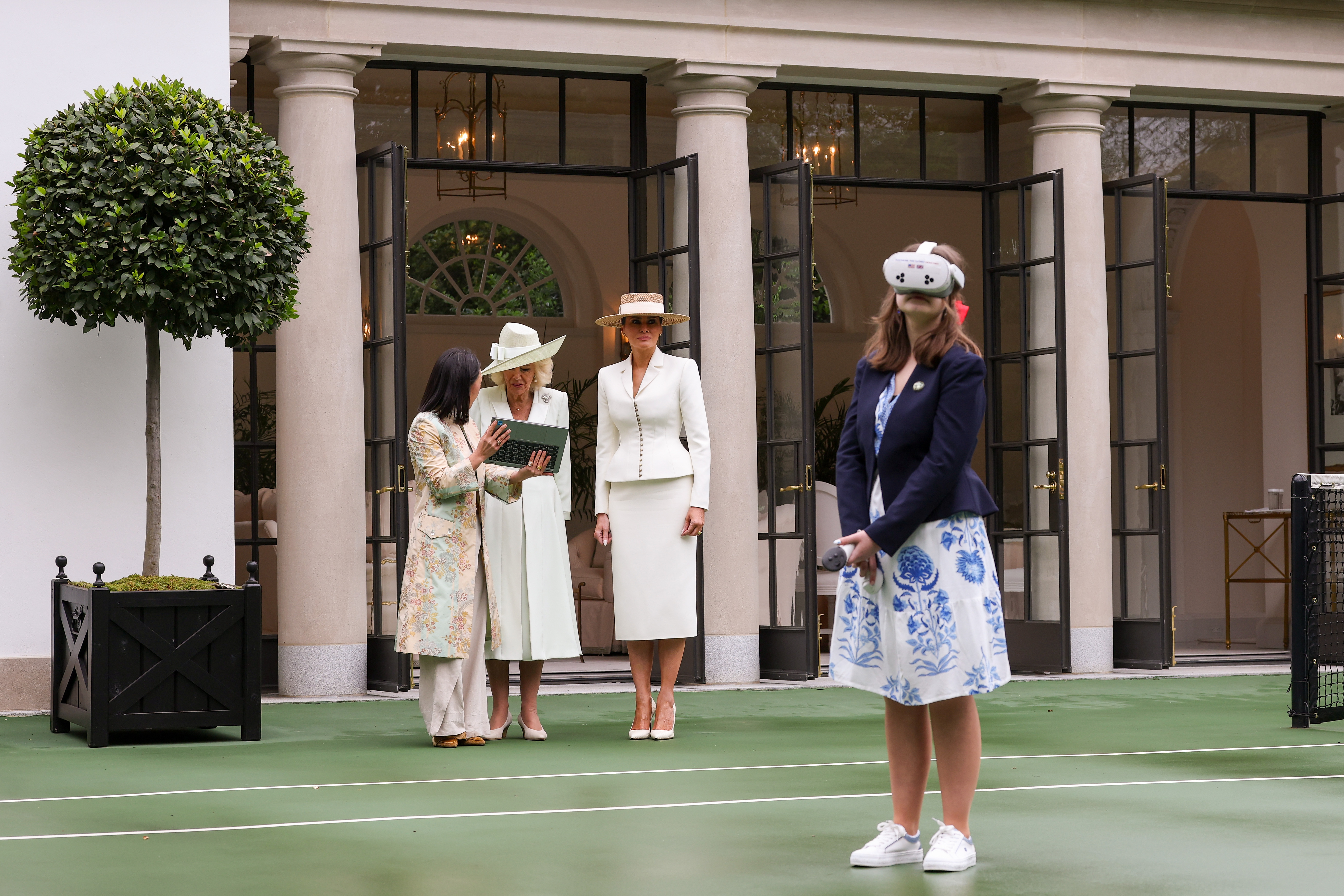 A student wears a virtual reality headset as Queen Camila and Melania Trump watch on.