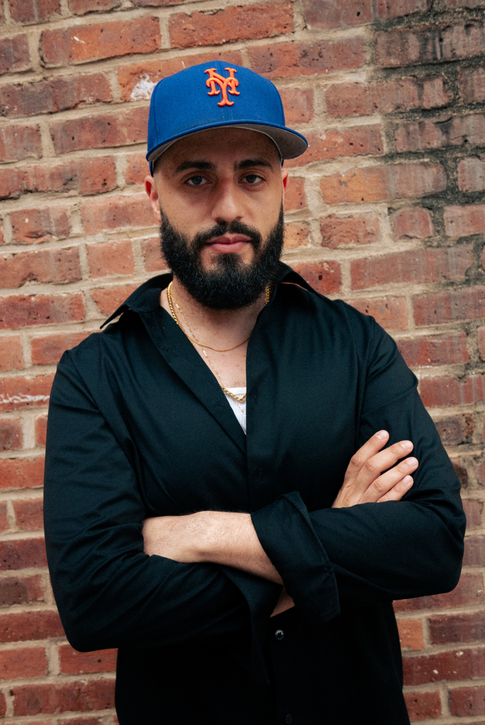 Dean Majd in front of brick wall wearing a baseball cap.