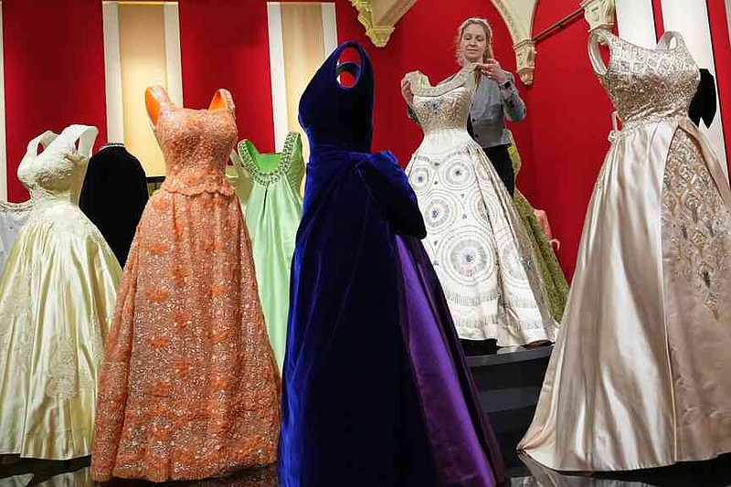 Cecilia Oliver, Textile Conservator at Royal Collection Trust adjusts a gown worn by Queen Elizabeth II, on display at 'Queen Elizabeth II: Her Life in Style' exhibition, to mark the centenary of the late queen's birth, at The King's Gallery at Buckingham Palace in London, Thursday, April 9, 2026. (AP Photo/Kirsty Wigglesworth)