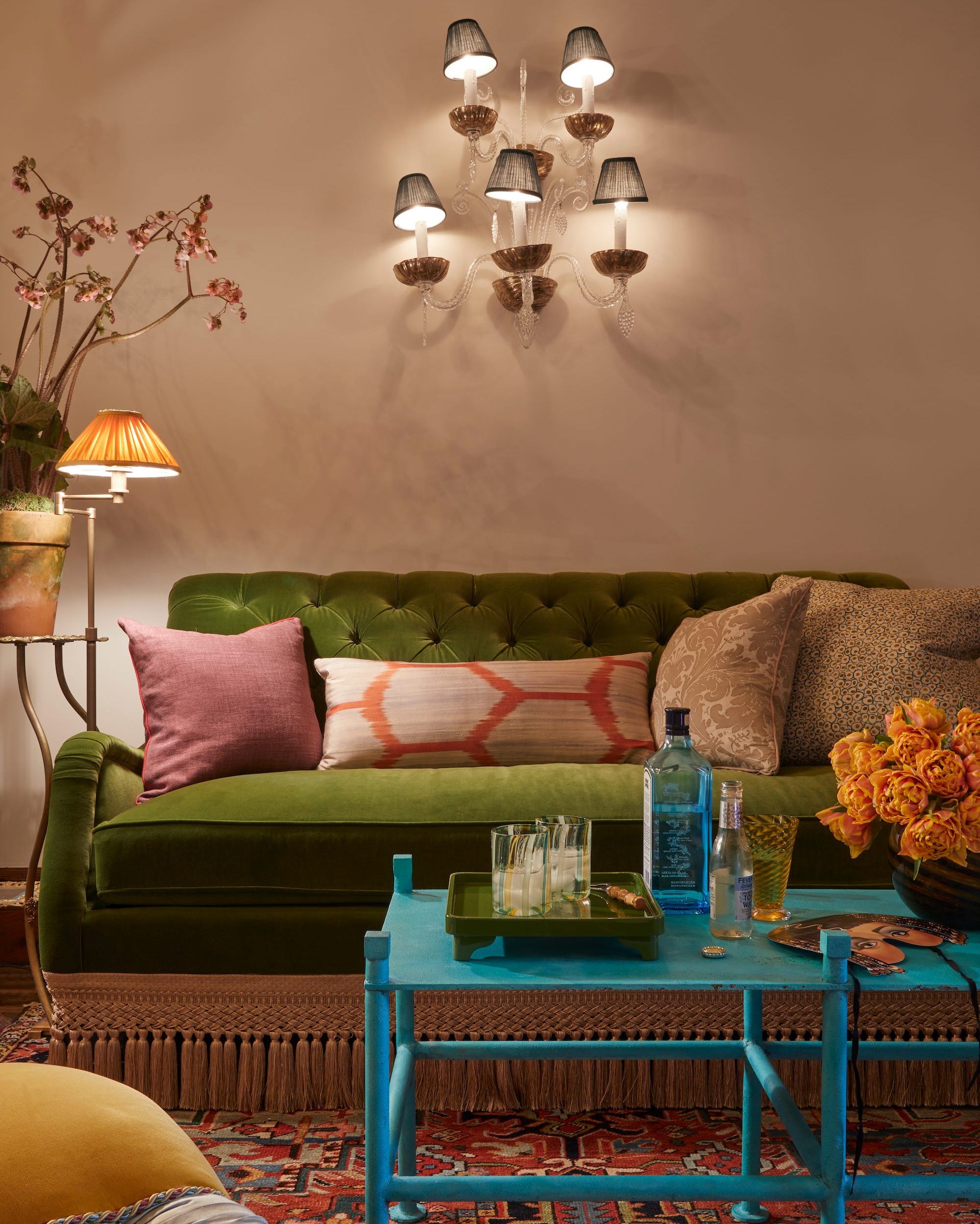 A stylish living room featuring a green sofa and layered lighting.