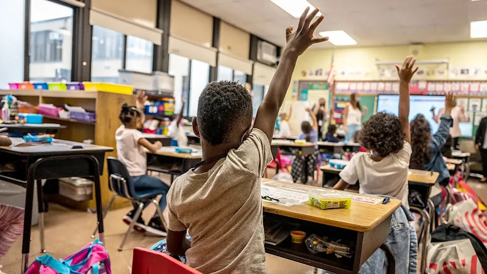 A student raises his hand in a classroom.