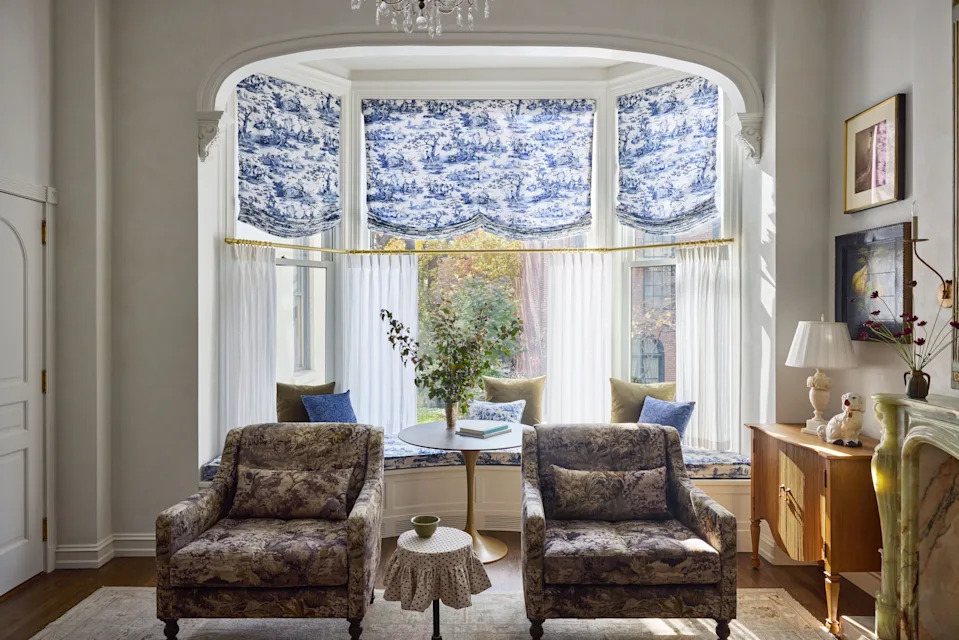 In both the living room and kitchen, the walls were plastered a creamy white hue by Michelle Kole. A martini table topped with a skirt, custom-made by Carey Trudeau in Schumacher’s Barlow print, sits between two Arhaus armchairs. To the right, an Arhaus chest is topped with an antique lamp and a vintage Staffordshire dog figurine from Painted Swan.