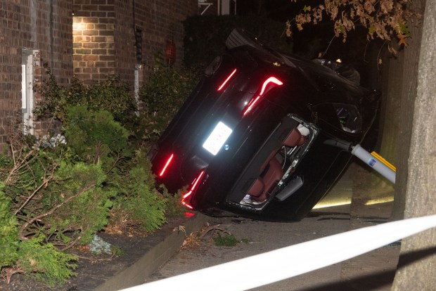 Police respond after a car overturned on the sidewalk on 37th Ave. and Parsons Blvd. in Queens on Sunday. The driver, Tao Wu, had just been shot in the back. (Gardiner Anderson/for New York Daily News)