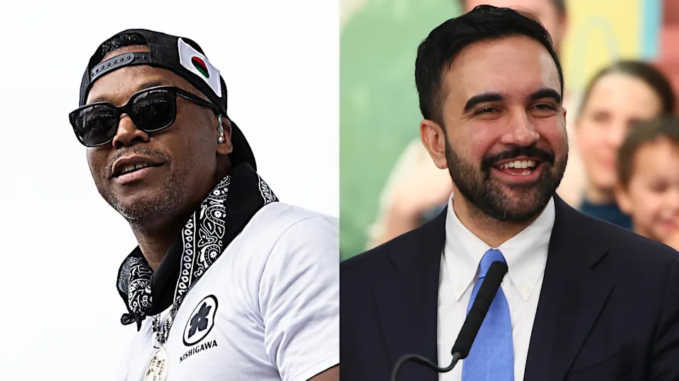 Lupe Fiasco in a white shirt and sunglasses, Zohran Mamdani in a suit with a blue tie, smiling at a microphone.