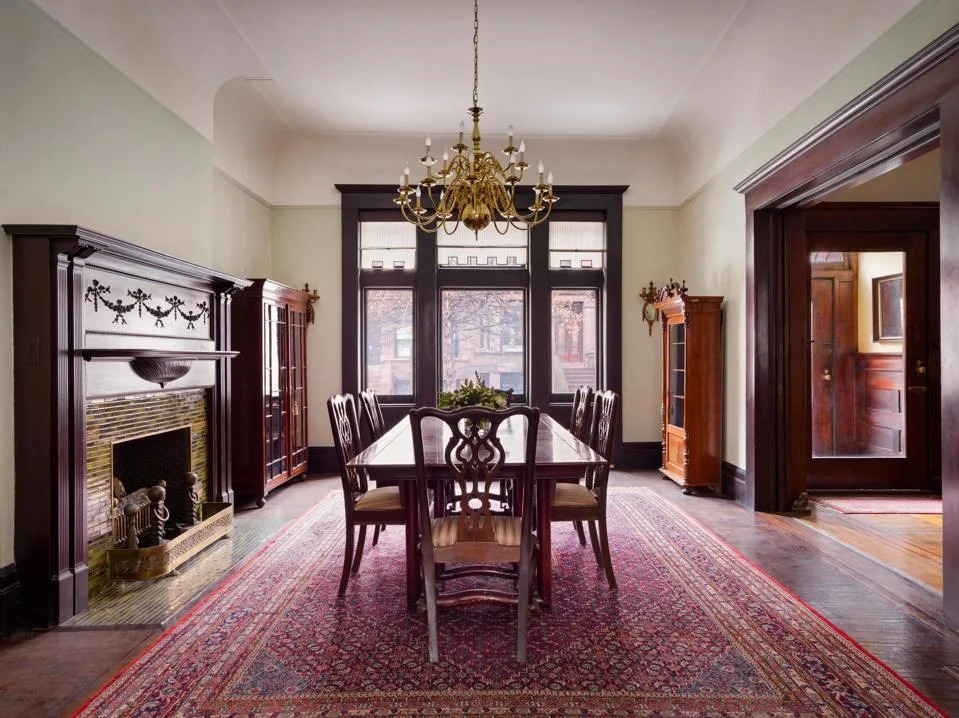 formal dining table and chairs next to a large traditional fireplace and generous wood-framed windows