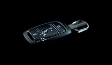 An extreme close-up photograph of a damaged car key fob reflecting a bright flash of light, conceptually representing the aftermath of a vehicle theft incident.