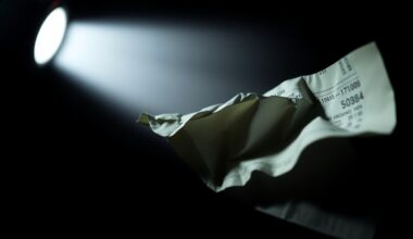 An extreme close-up of a crumpled financial document reflecting harsh, direct lighting, conceptually illustrating the gritty details of a financial crime case.