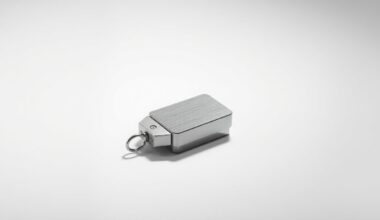 A close-up photograph of a polished metal supply chain device, such as a barcode scanner or RFID tag, arranged elegantly on a clean, monochromatic background and dramatically lit to convey the abstract concepts of logistics software and data-driven decision making.