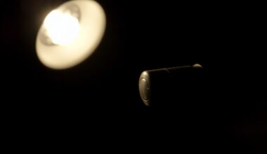An extreme close-up photograph of a small piece of physical evidence from the subway shooting, such as a spent shell casing or bullet fragment, lit by a harsh, direct camera flash against a pitch-black background, creating a stark, gritty, investigative aesthetic.