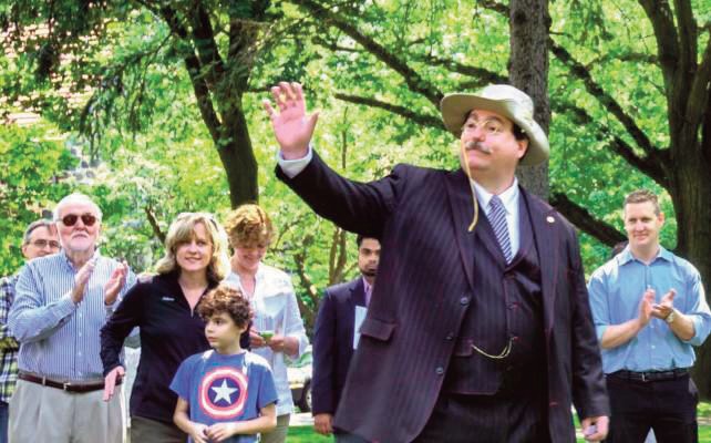 Flag Day, 2017, Bill is on the far left clapping as President Teddy Roosevelt made a guest appearance at the Forest Hills Gardens Flag Day Celebration in honor of the 100th Anniver­sary of TR’s famous speech made at Station Square in For­est Hills. Professor Coleman is seen here with then-Queens Borough President Melinda Katz and her son Carter Katz and Assemblyman Andrew Hevesi.
