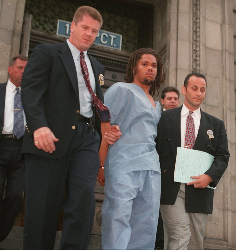 Shatiek Johnson, in light blue scrubs, is escorted by detectives outside the 120th Precinct.
