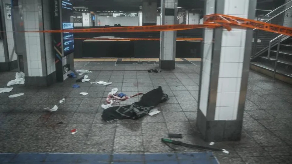 Orange crime tape is used to cordon off the scene of  blood and a machete on the train platform after a man was shot by New York Police Department.