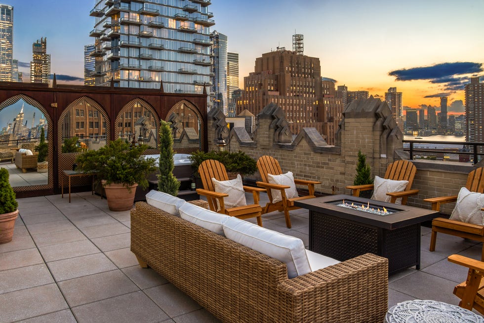 Rooftop terrace with seating and city skyline view at sunset
