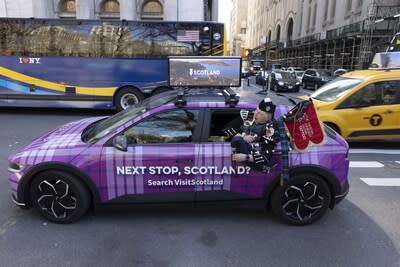 A piper from The Royal Edinburgh Military Tattoo poses alongside a VisitScotland tartan taxi in Manhattan. Credit: VisitScotland / Andrew Kelly