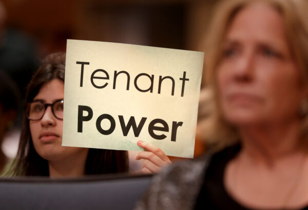 People hold up signs during a public meeting of the Rent Guidelines Board in New York, Monday, June 8, 2015. Photo: Seth Wenig/AP