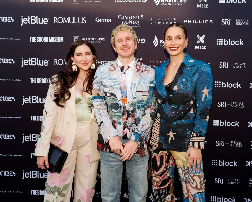 A trio of attendees posing on a step-and-repeat backdrop featuring sponsor logos at The Bronx Museum gala.
