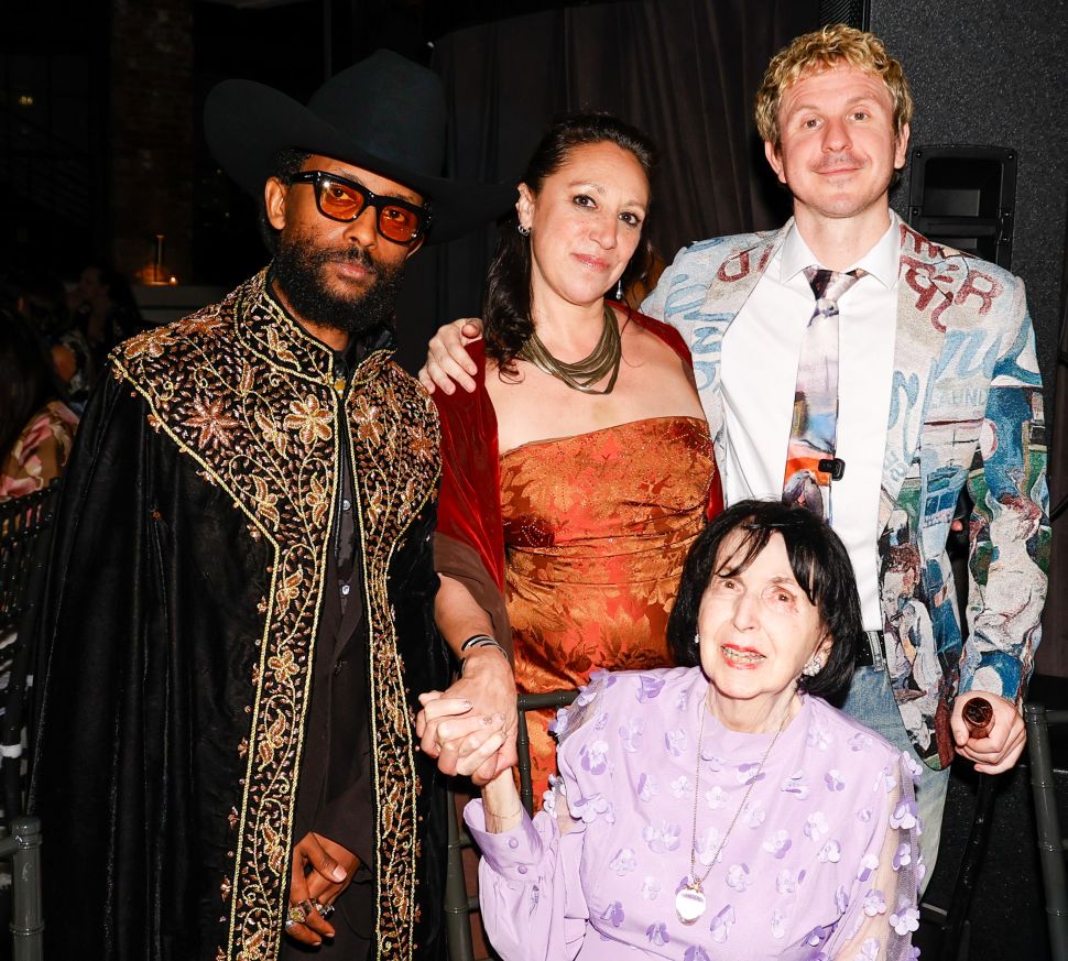 A group of four guests, including one seated elderly woman, posing together at a gala table in evening attire.