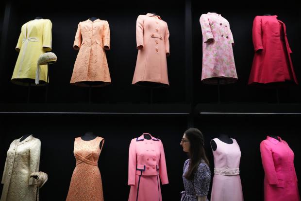 A member of Royal Collection Trust staff looks towards day wear worn by Princess Elizabeth, on display at 'Queen Elizabeth II: Her Life in Style' exhibition, to mark the centenary of the late queen's birth, at The King's Gallery at Buckingham Palace in London, Thursday, April 9, 2026. (AP Photo/Kirsty Wigglesworth)
