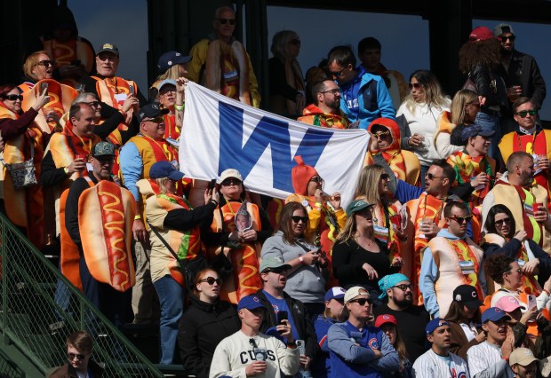 Fans wearing hot dog costumes hold a "W" flag after a 4-2 Cubs win over the Mets on Saturday, April 18, 2026, at Wrigley Field. (John J. Kim/Chicago Tribune)