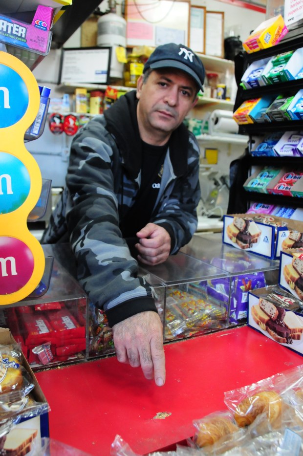 Ahmed Hussein, then a clerk at the 1738 Finest Deli in the Bronx, points to where a robber's bullet hit the counter in 2015. (Michael,l Schwartz for New York Daily News)