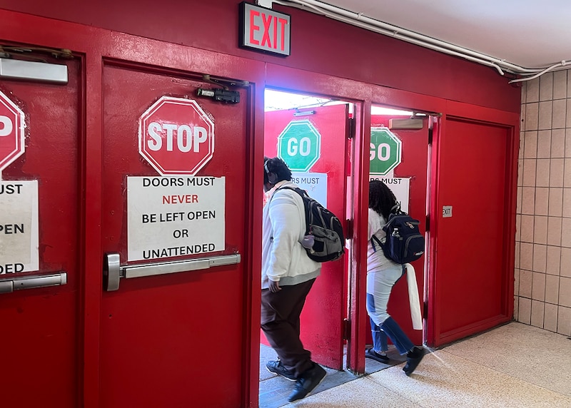 Students walk through a wall of red doors.