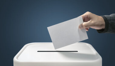 Man putting a ballot paper envelope into a voting box concept for election, freedom and democracy