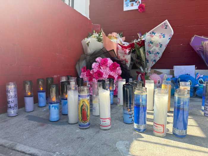Candles, flowers, and buzzballs are left to commemorate the lives of one of the victims who lived a block away from the fire.