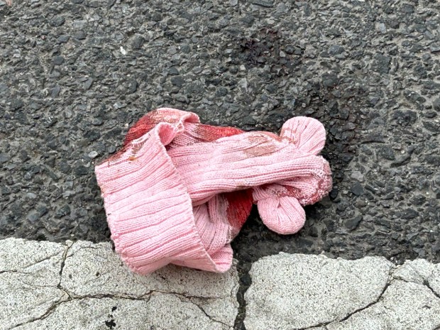 A bloody pink knit baby's bonnet is pictured in the crosswalk at Debevoise St. and Humboldt St. in Brooklyn, after a 7-month-old girl was fatally shot on Wednesday, April 1, 2026. (Kerry Burke / New York Daily News)