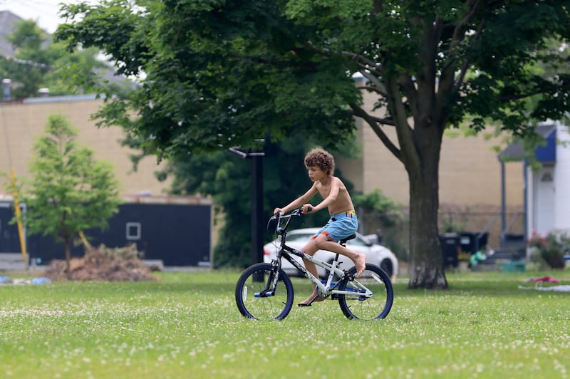 A child rides a bike across Washington Square Park on Syracuse's North Side. High temperatures in the 90-degree range forced city schools to close for a half day on Tuesday, June 18, 2024. (Katrina Tulloch)