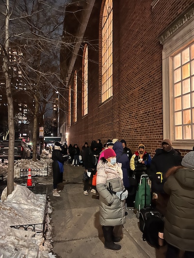 People line up on the street to receive food distributions.