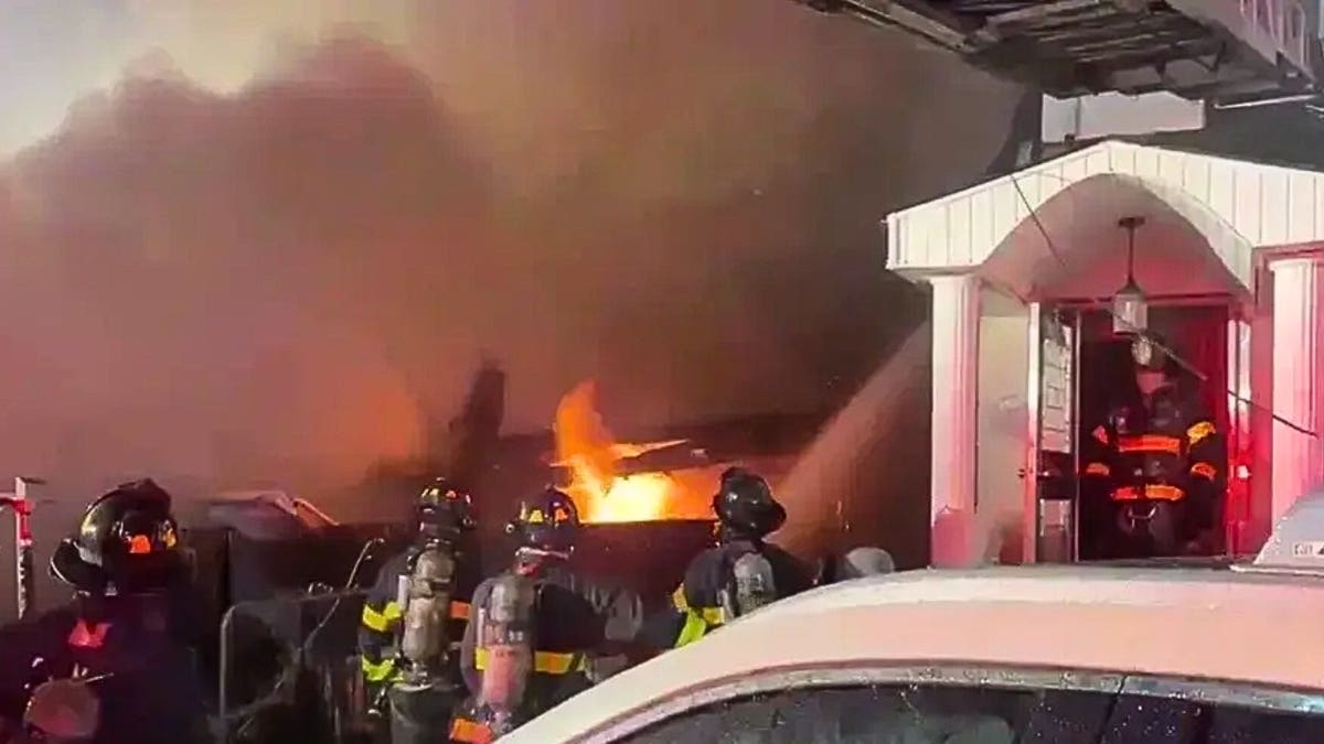 Firefighters spray water on a large home fire